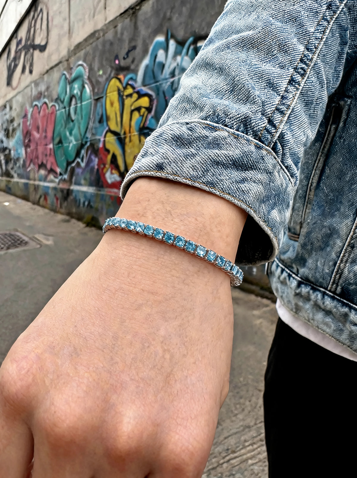 Tennisarmband am Handgelenk mit blauen Zirkonia-Steinen im schmalen Silberband